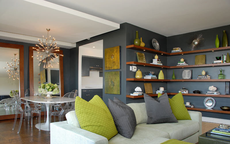 Enfeites verdes dão vida à estante com fundo cinza